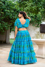 Load image into Gallery viewer, Elegant blue chiffon lehenga with floral prints and pearl blouse , Shop sky-inspired blue lehenga for weddings and festive events , Blue floral print lehenga with 9-meter flair and stitched blouse , Premium chiffon lehenga in blue with micro cotton inner .