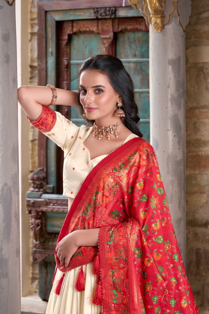 Elegant cream lehenga choli in tussar silk fabric , Cream printed lehenga with foil work and dupatta , Traditional cream lehenga set for wedding events , Cream lehenga with tassel dupatta and lace border .
