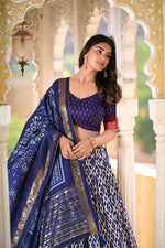 Load image into Gallery viewer, Blue half saree set includes a stitched tussar silk lehenga with ikkat print and foil work, fitting up to a 42-inch waist with a drawstring and zip closure. The lehenga features a canvas lining and cancan for volume, with a 3.8-meter flair and micro cotton inner. The unstitched blouse piece matches the lehenga fabric and design.
