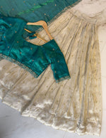 Load image into Gallery viewer, Traditional tissue silk ensemble featuring stitched gold zari lehanga, unstitched embroidered blouse material, and ornate voni with detailed cut work border.
