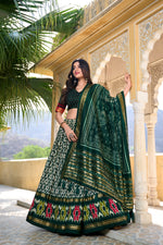 Load image into Gallery viewer, Green foil print lehenga in traditional tussar silk , Wedding special green lehenga with ikkat motifs , Trending green lehenga with shimmer and lace border , Luxurious green lehenga with embroidery-style foil print , Classic green lehenga choli for bridal and celebration wear . 
