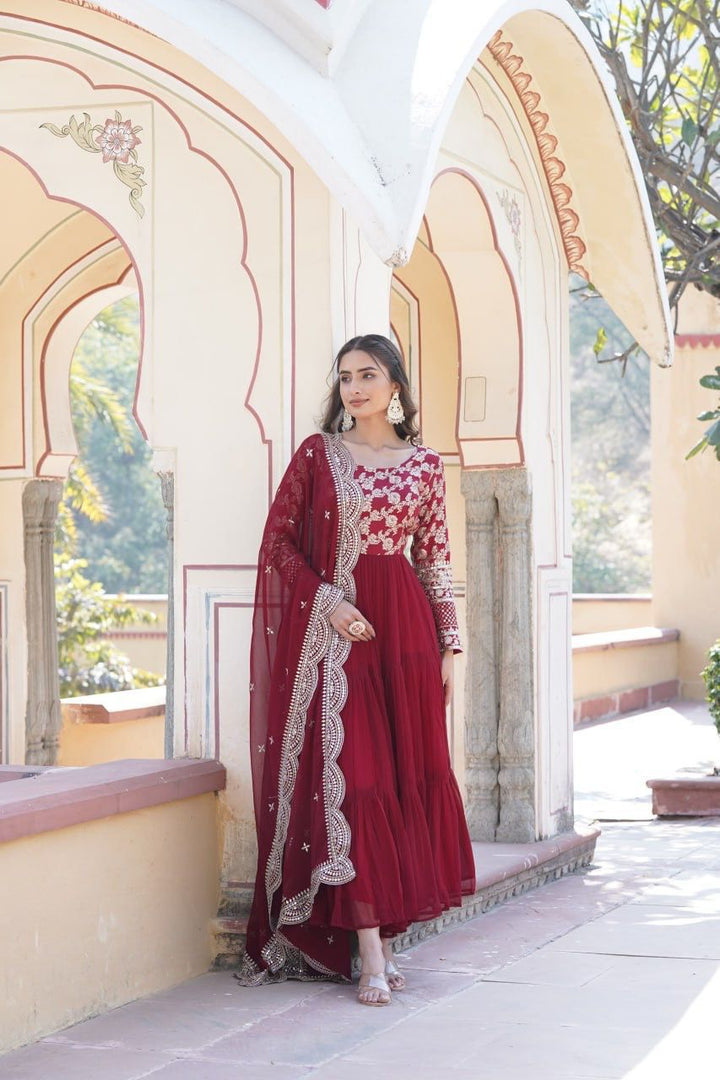 Maroon Faux Blooming Gown With Jacquard Sequins & Cut-Work Dupatta Anarkali WIth Price Under 2000 . this Fabric Sophisticated faux blooming gown with viscose dyable jacquard fabric, full sleeves, and frill stitching. Complete with a cut-work dupatta for festive elegance .