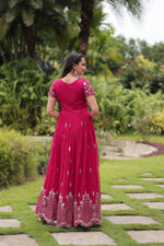 Load image into Gallery viewer, Luxurious Rani Pink Faux Blooming gown featuring Zari Sequins embroidery. 55-inch length with 3.5-meter flair, complete cotton lining, short sleeves, and round neckline.
