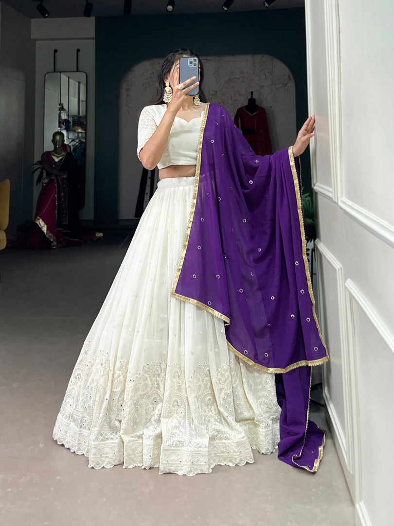 White stitched lehenga choli with cotton lining and 3.5m flair , White wedding lehenga with detailed mirror craftsmanship , White georgette lehenga with modern traditional fusion , Classy white mirror lehenga with matching embroidered dupatta . 